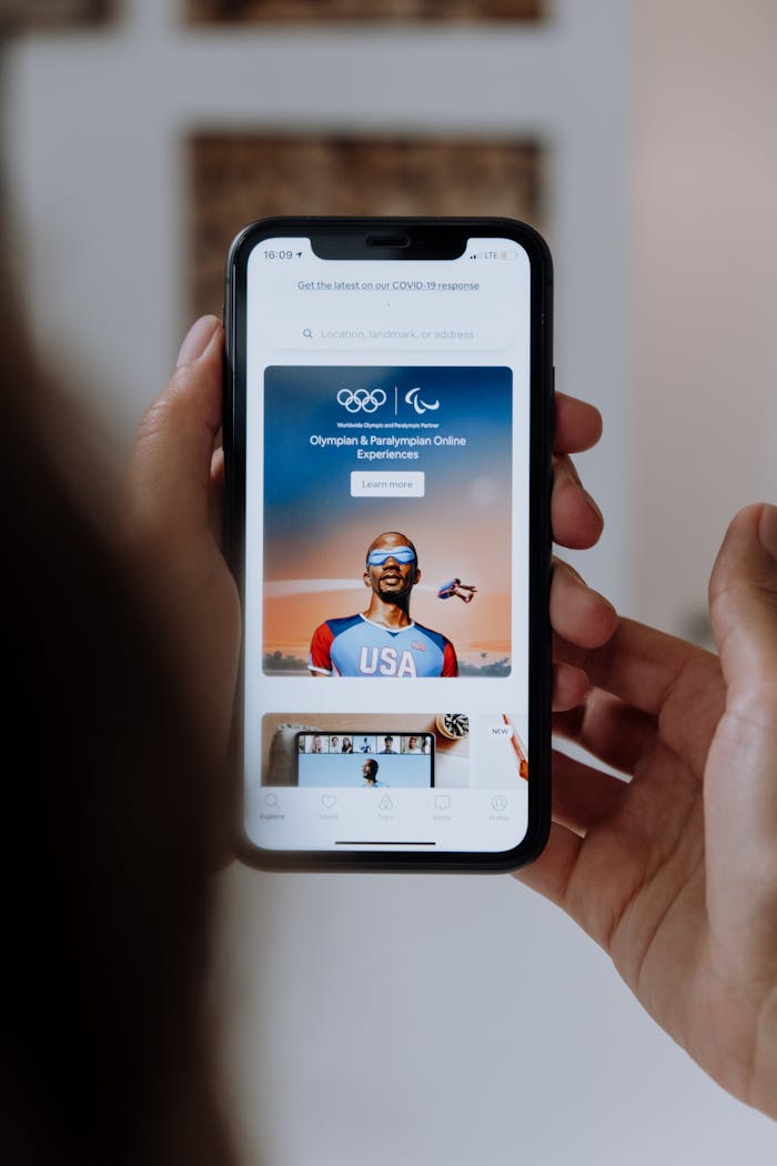 Person holding a smartphone showing Olympic and Paralympic online experiences.
